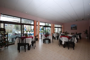 A restaurant with multiple tables, chairs, and potted plants.