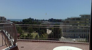Un balcón con vista a un paisaje urbano, que incluye edificios y una masa de agua.