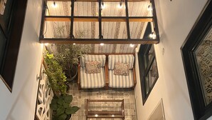 A cozy lounge area with a wooden ceiling, striped cushions, and potted plants. - La casa del Viajero (Lima)