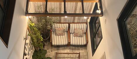 A cozy lounge area with a wooden ceiling, striped cushions, and potted plants.