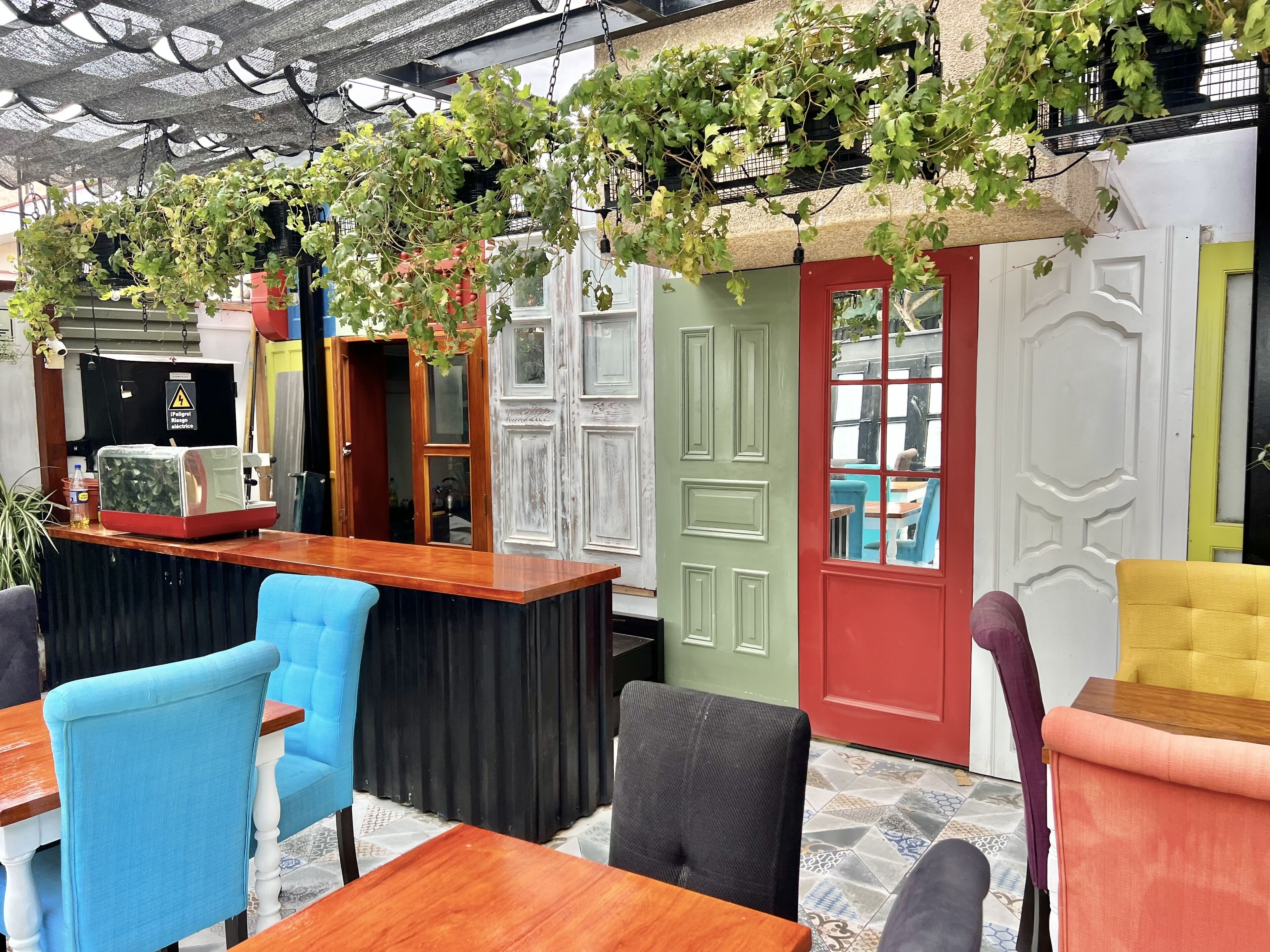 A cozy indoor seating area with a wooden counter, blue and black chairs, and a green door.