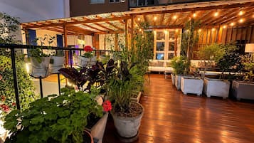 Un patio al aire libre con piso de madera, plantas en macetas y un conjunto de asientos.