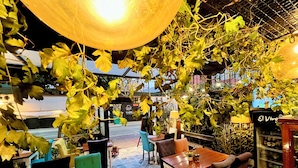 An outdoor seating area with tables and chairs, surrounded by greenery and a patterned floor. - La casa del Viajero (Lima)