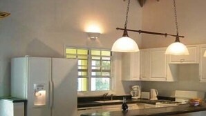 Una cocina con isla central, armarios blancos e iluminación colgante.