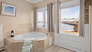A bathroom with a large bathtub, a window with a view of a body of water, and a framed picture on the wall. - The Beacon Waterfront Inn (Hull)