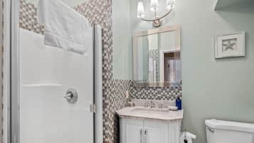 A bathroom with a shower, a sink with a mirror, and a toilet.