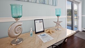 A reception area with a marble counter, two teal glass lamps, a framed mask policy sign, a starfish decoration, and a door leading to an outdoor area. - The Beacon Waterfront Inn (Hull)