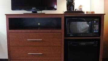 A wooden cabinet with a television, a microwave, and a small refrigerator.