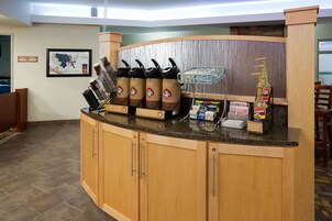 Una estación de café con varios dispensadores de café, un dispensador de agua y una pizarra con el menú.
