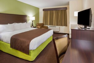 Habitación de hotel con una cama grande, televisión, aire acondicionado, una silla y un escritorio.