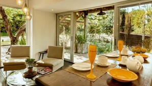 A modern living room with a glass coffee table, two sofas, and a dining area with a table set for breakfast. - CDL - containers design loft (José Ignacio)