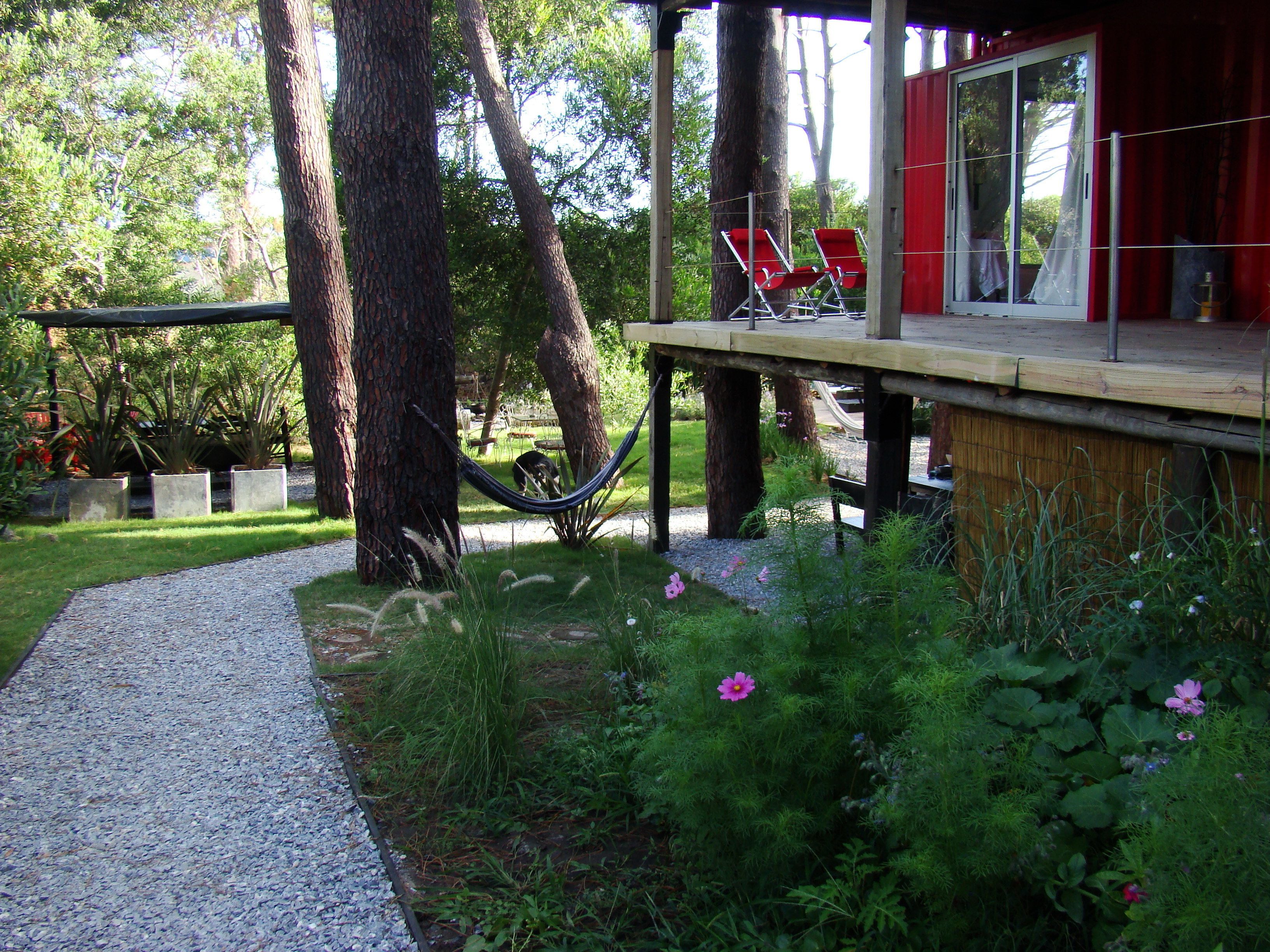 A covered outdoor area with a wooden deck, two red chairs, and a hammock.