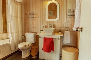 A wooden-paneled bathroom with a white toilet, a sink, and a bathtub. - BDL - beach design loft (José Ignacio)