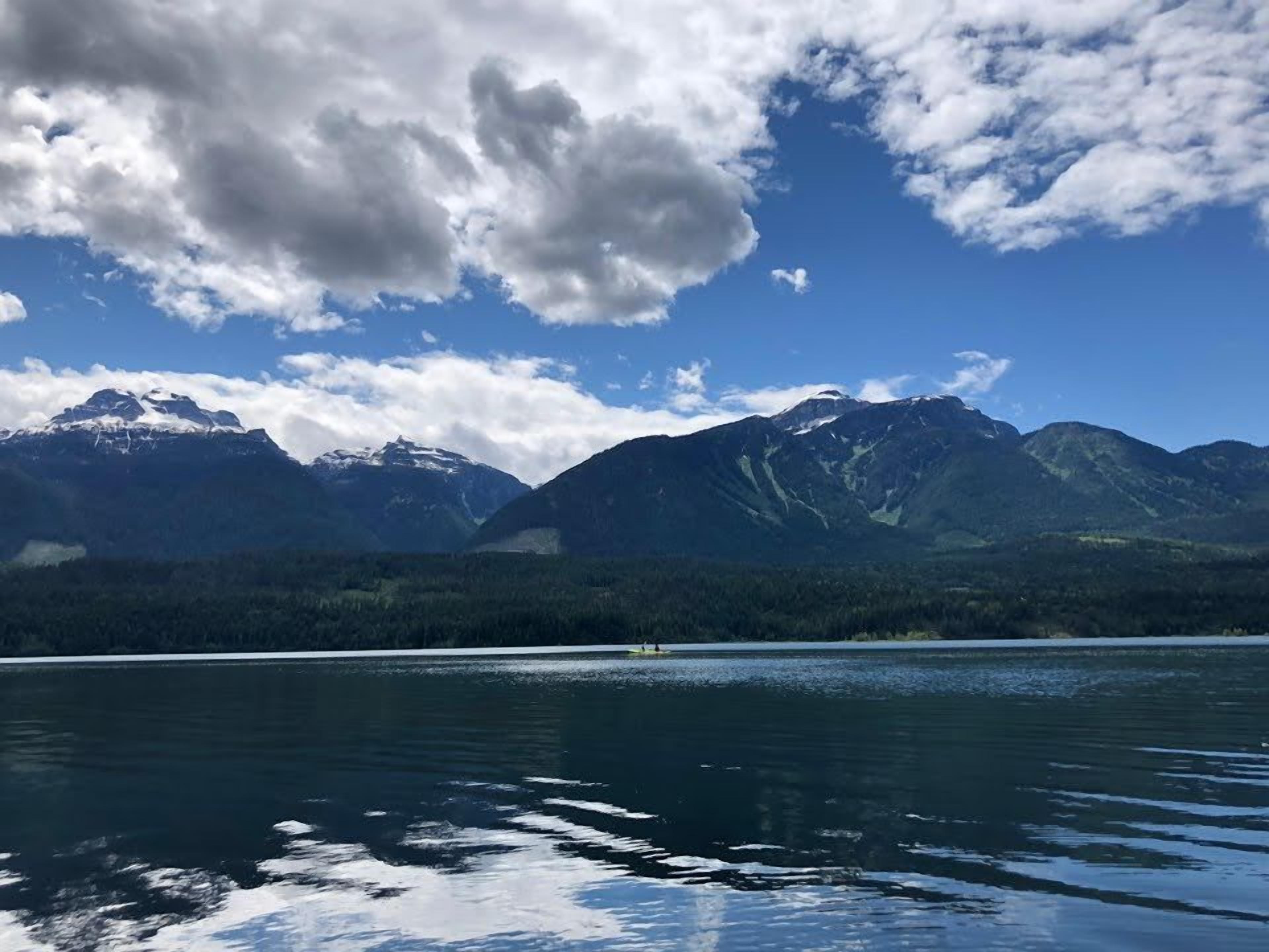 Un lago con montañas al fondo y un cielo parcialmente nublado.