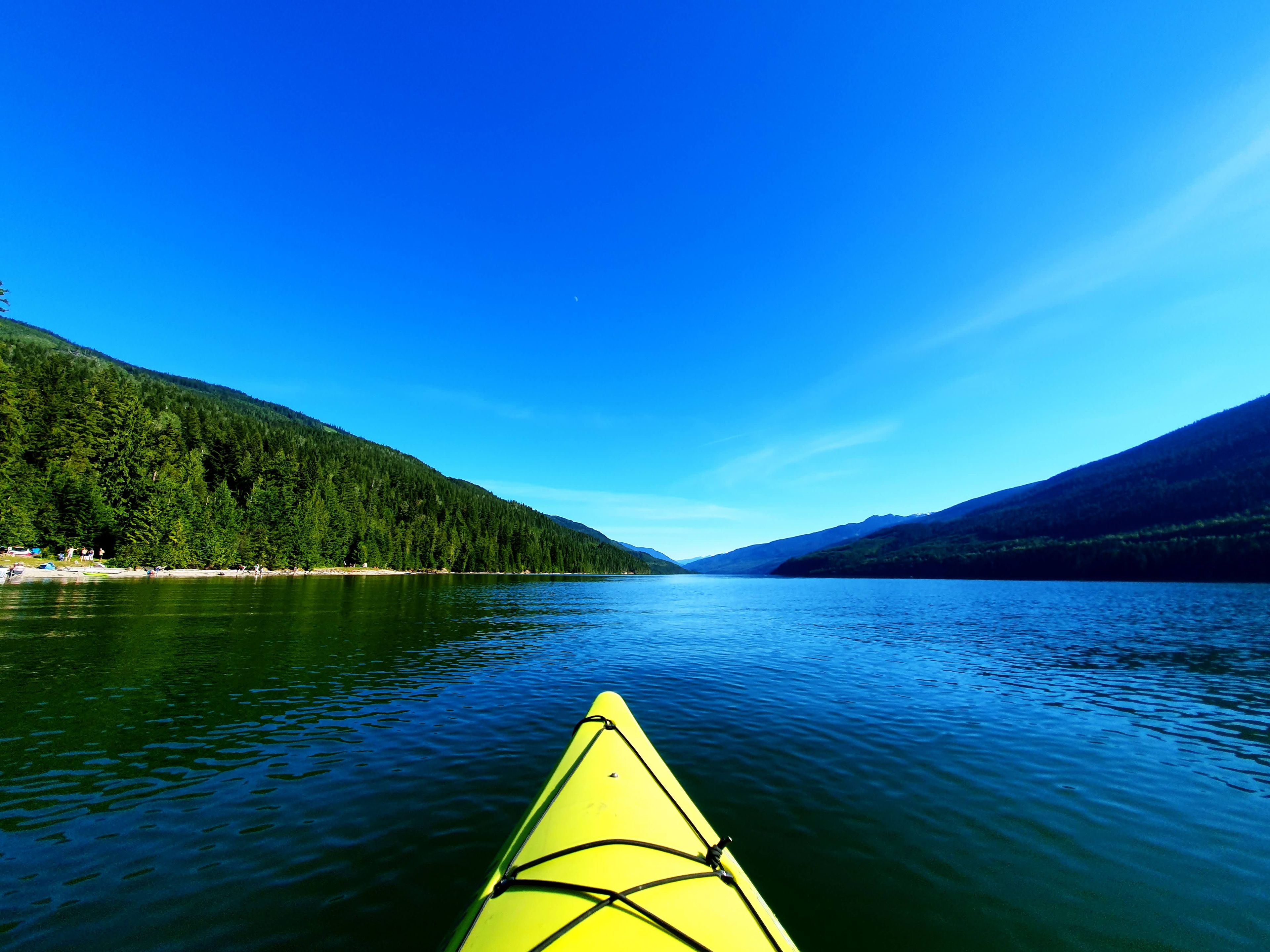 A kayak on calm water with forested hills in the background.