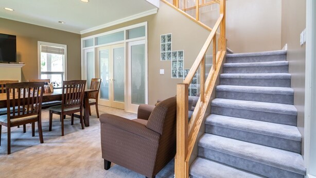 A spacious living area with a staircase, a dining table with chairs, and a sofa. - Cornerstone Bed and Breakfast (Revelstoke)
