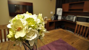 A dining table with a bouquet of flowers in the foreground. - Cornerstone Bed and Breakfast (Revelstoke)