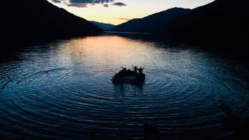 Un lago tranquilo con un bote en el centro rodeado de montañas.