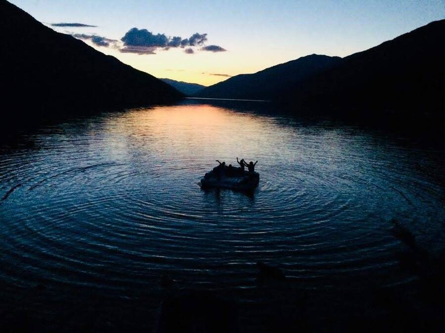 Un lago tranquilo con un bote en el centro rodeado de montañas.