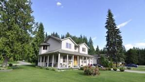 A two-story house with a porch, surrounded by a well-maintained lawn and trees. - Cornerstone Bed and Breakfast (Revelstoke)