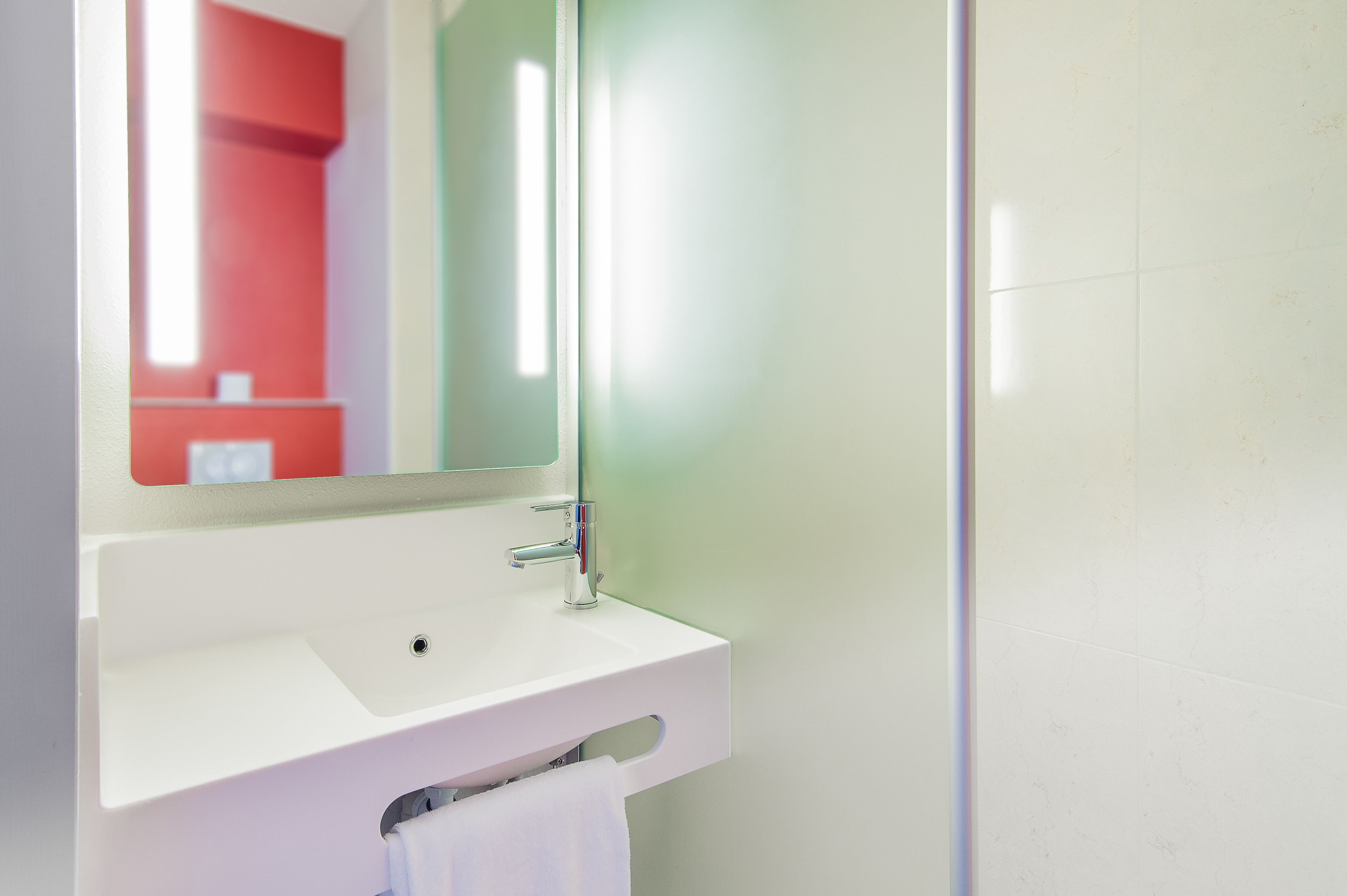 Une salle de bain avec un lavabo blanc, un miroir et un meuble rouge.