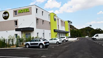 Un hôtel-restaurant de type « bed and breakfast » au design moderne, doté d’un parking où sont stationnées plusieurs voitures et d’un fourgon blanc.