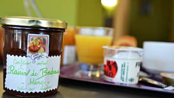 Et glas Confiture extra Raisin de Bordeaux blanc på et fad med et glas appelsinjuice og en lille skål yoghurt.