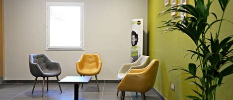 A waiting area with modern chairs, a table, and a potted plant.