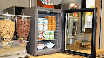 A self-service beverage station with various drink dispensers and a refrigerated display case with snacks and dairy products.