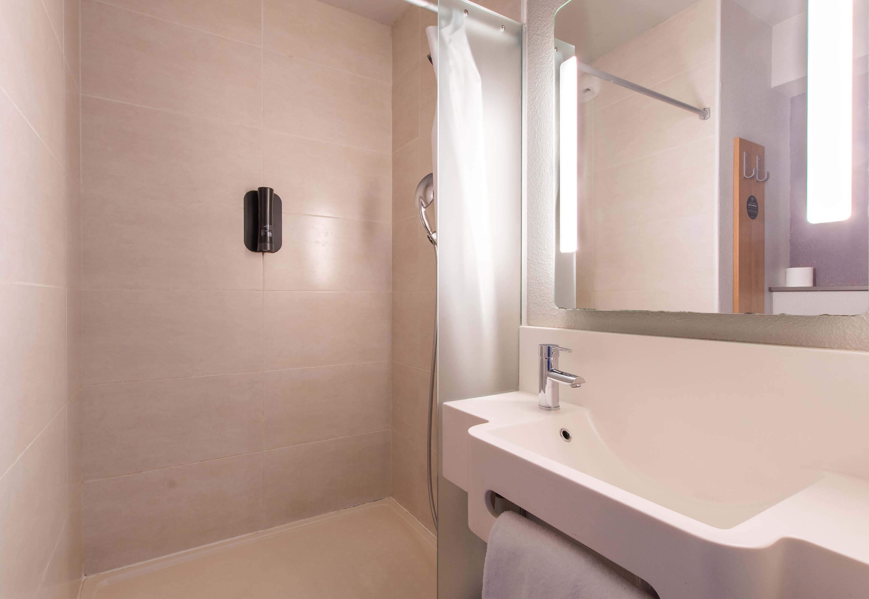 Ein modernes Badezimmer mit Dusche, Waschbecken und Spiegel.