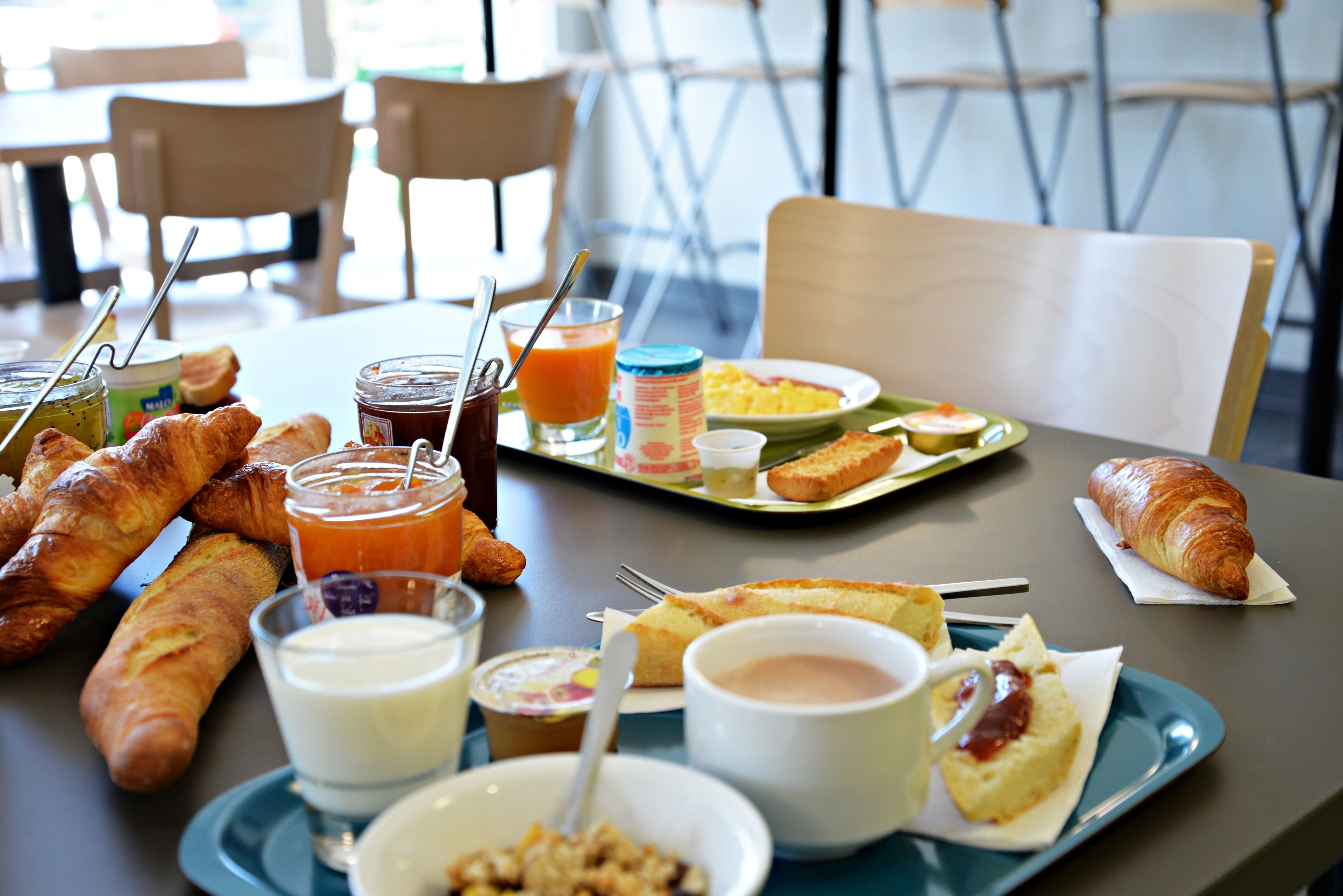 Una mesa de desayuno con cruasanes, pastelería y diversas opciones para untar.