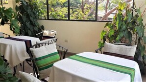 A dining area with tables and chairs, surrounded by plants. - Árbol de Fuego Eco-hotel, a green experience in the city (Antiguo Cuscatlán)