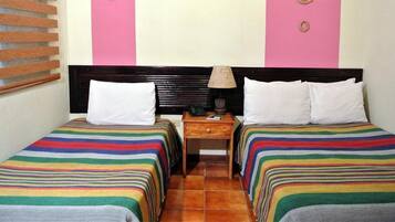 A room with two beds, each with a striped bedspread, a nightstand with a lamp, and a wall with a circular decoration.