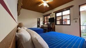 A room with two beds, a ceiling fan, a TV, and a window with a view. - Árbol de Fuego Eco-hotel, a green experience in the city (Antiguo Cuscatlán)
