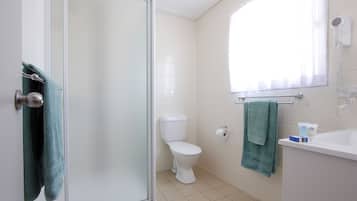 A bathroom with a toilet, a sink, a towel rack, and a shower door.