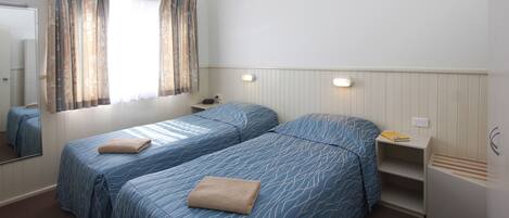 Un dormitorio con dos camas, una mesita de noche, un espejo y una ventana con cortinas.