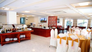 Un espace de restauration d’hôtel avec un buffet, plusieurs tables et des chaises.