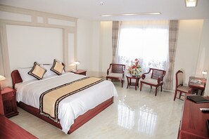 A hotel room with a large bed, two bedside tables, a desk with a chair, and a window with curtains. - Minh Tam Phu Nhuan Hotel & Spa (Ho Chi Minh City)