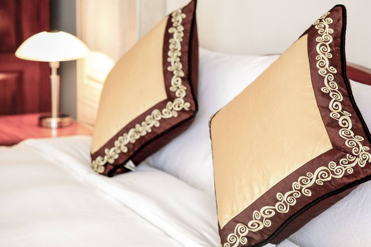 Una cama con dos almohadas y un borde decorativo.
