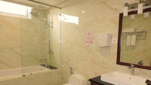 Une salle de bain avec une douche à parois de verre, des toilettes blanches, un lavabo avec un miroir et un porte-serviettes.