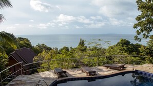 A swimming pool with lounge chairs, a staircase, and a view of the sea. - Haad Yao Over Bay Resort (Ko Pha-ngan)