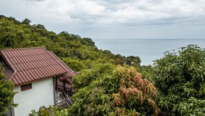 A traditional building with a sloped roof, surrounded by lush greenery and overlooking a body of water. - Haad Yao Over Bay Resort (Ko Pha-ngan)
