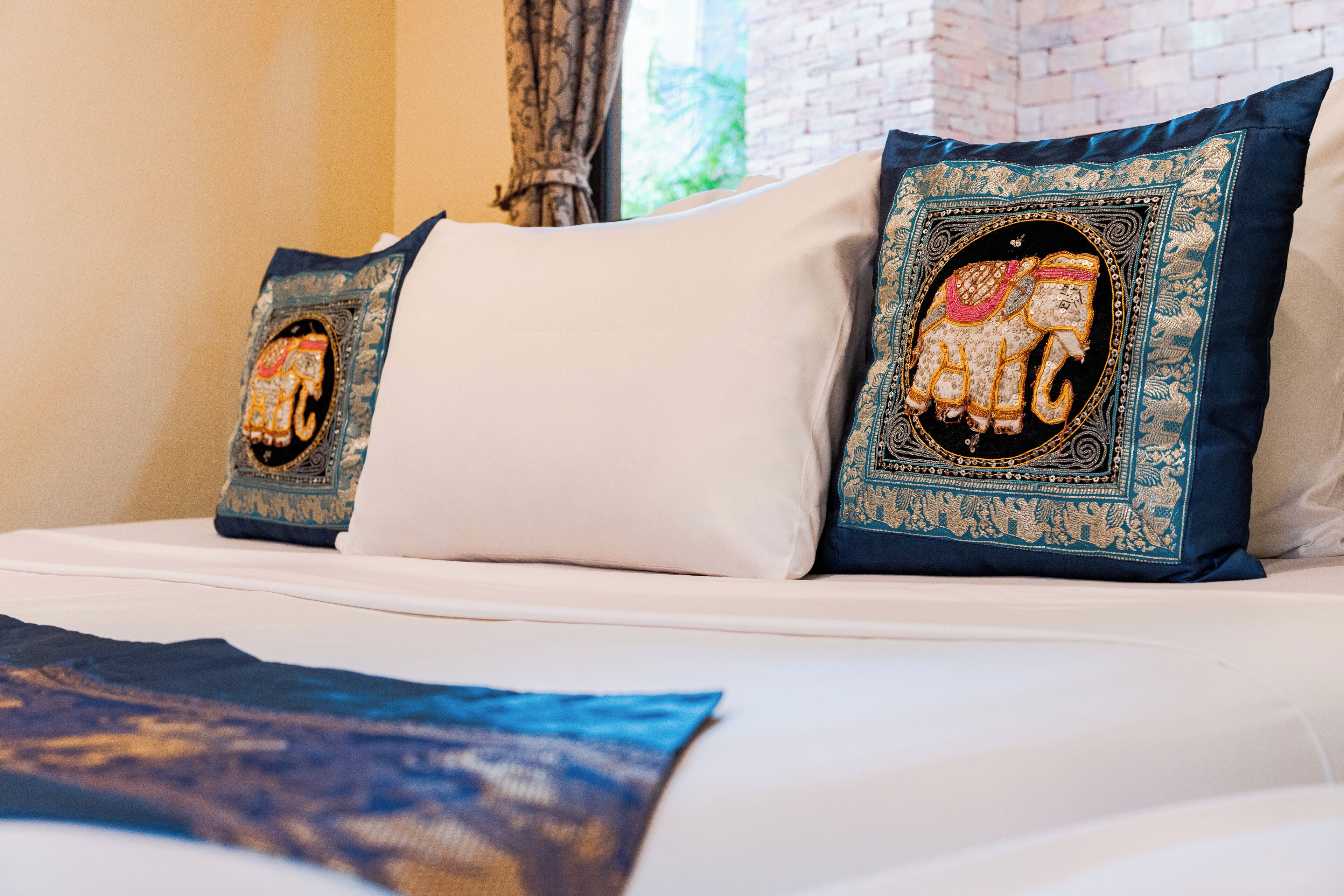 A bed with two decorative pillows featuring elephant designs.