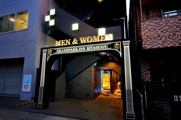 The entrance to Grandpark Inn Kitasanju, featuring a prominent 'MEN & WOMEN' sign and a well-lit pathway leading inside. - Spa & Capsule Hotel Grandpark Inn Kitasenju (Tokyo)