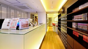 A hotel reception area with a glass counter, informational brochures, and a well-lit interior. - Spa & Capsule Hotel Grandpark Inn Kitasenju (Tokyo)
