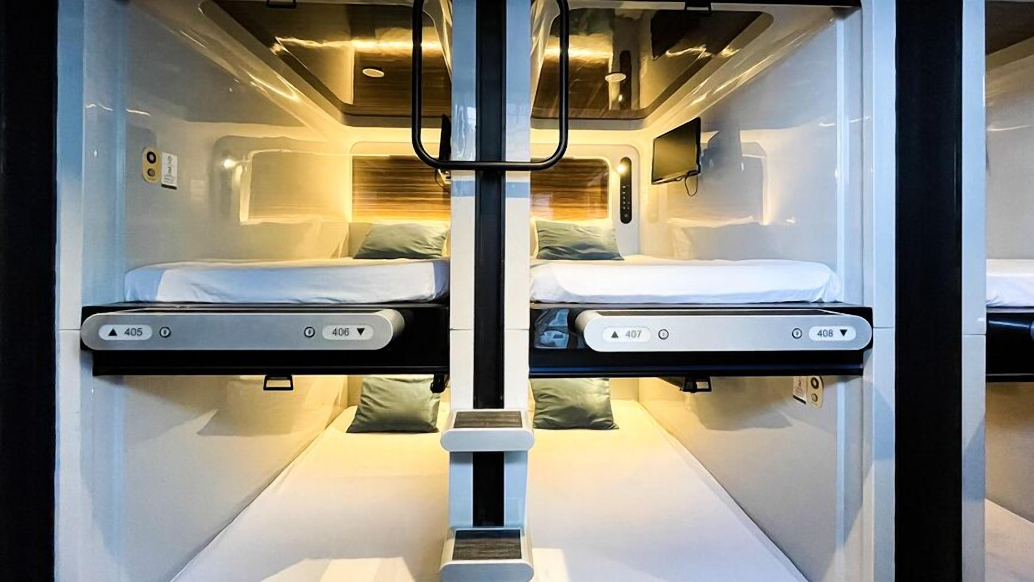 A train compartment with two beds, each with a control panel, and overhead lighting.