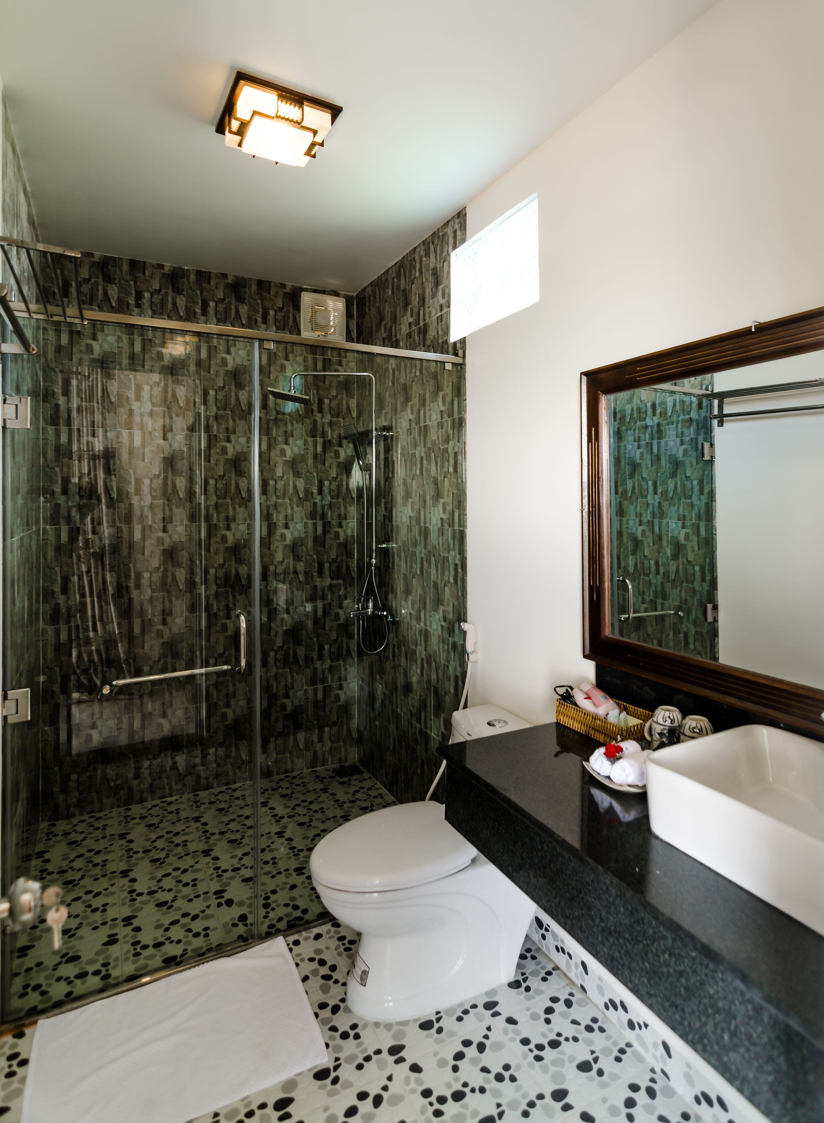 Un baño moderno con ducha de vidrio, inodoro blanco y un espejo grande.