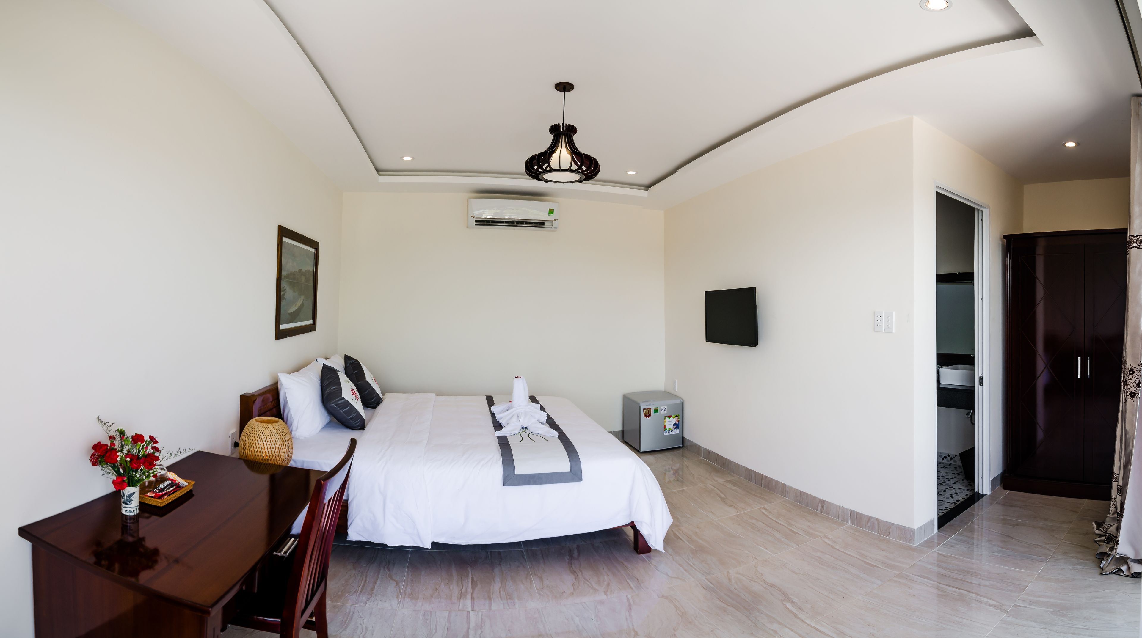 A bedroom with a bed, bedside table, lamp, air conditioning unit, and a wardrobe.