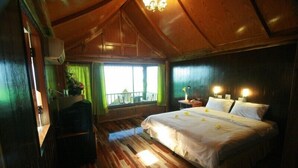 Un dormitorio con suelo de madera, cama, lámparas de noche y vistas al exterior a través de una ventana.