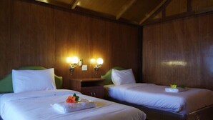 Habitación de hotel con dos camas, paredes de madera y luces fijadas a la pared.